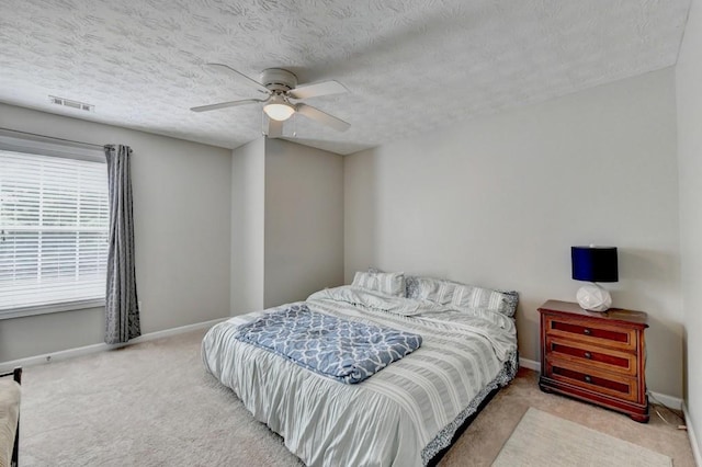 carpeted bedroom featuring ceiling fan and a textured ceiling