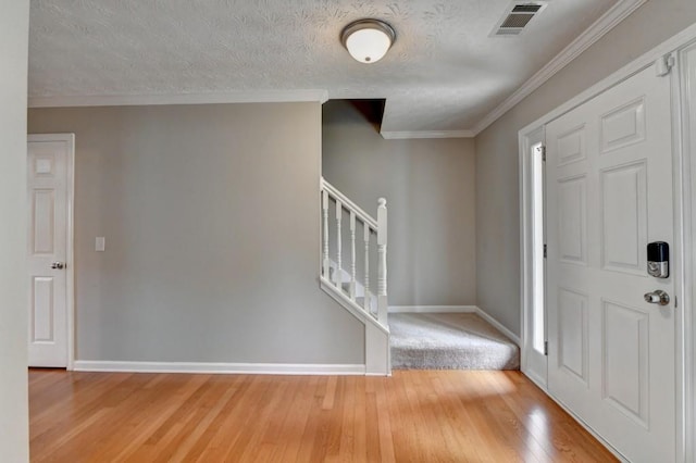 foyer with hardwood / wood-style floors, a textured ceiling, and ornamental molding