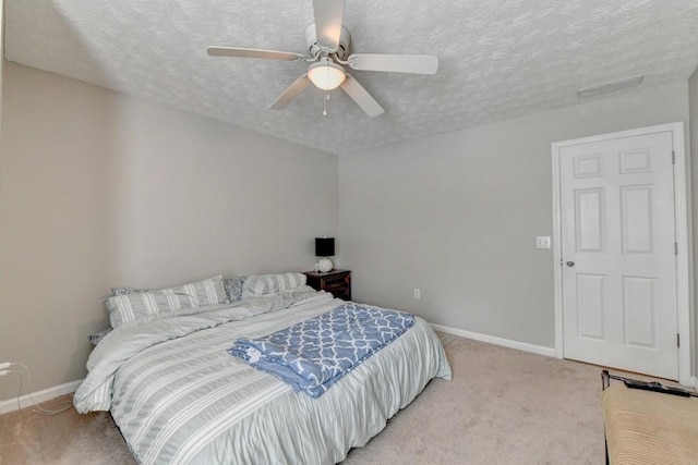 carpeted bedroom featuring ceiling fan and a textured ceiling