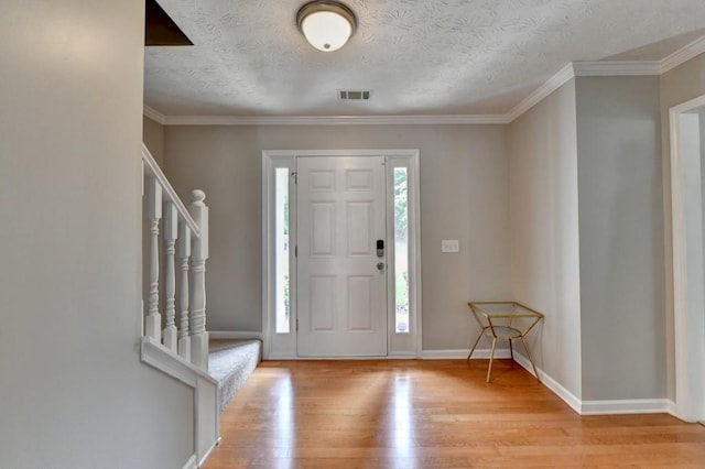 foyer featuring crown molding, a textured ceiling, and light wood-type flooring