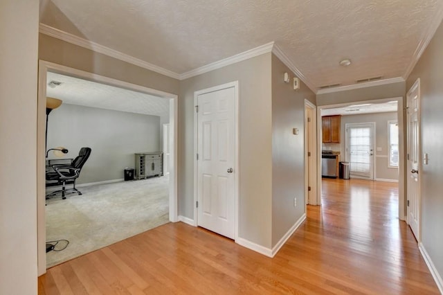 corridor with crown molding, light wood-type flooring, and a textured ceiling