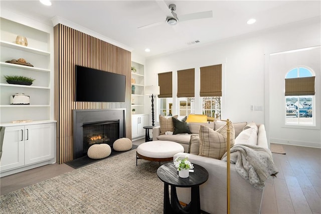 living room with ceiling fan, built in shelves, and light hardwood / wood-style floors