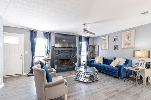 living room featuring hardwood / wood-style floors, a fireplace, a healthy amount of sunlight, and ceiling fan