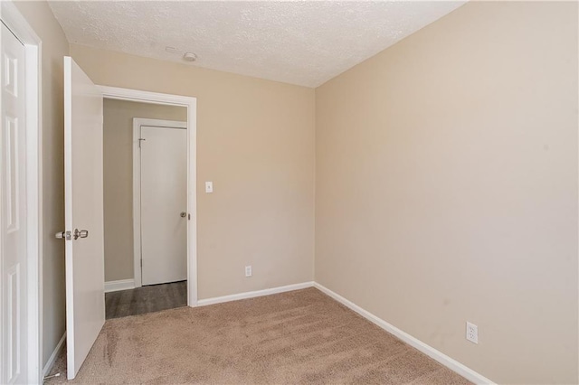 spare room featuring light colored carpet and a textured ceiling