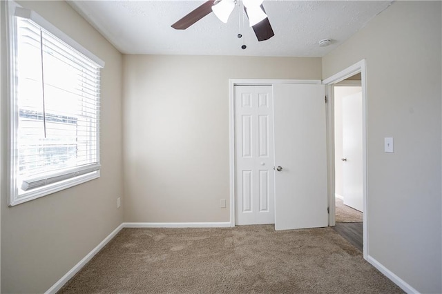 unfurnished bedroom featuring ceiling fan, a closet, carpet floors, and multiple windows