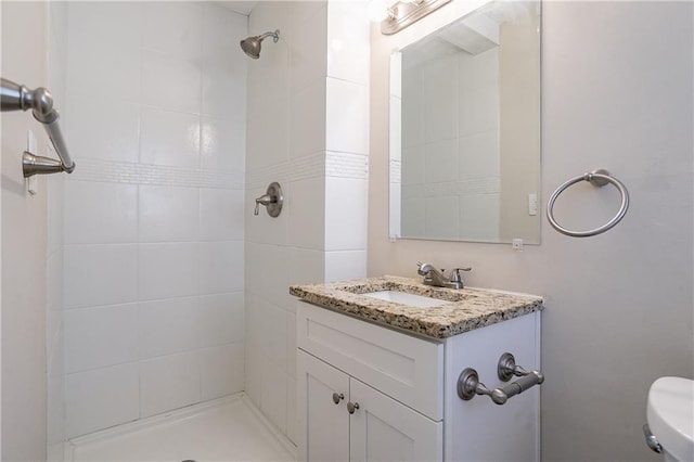 bathroom with toilet, vanity, and a tile shower