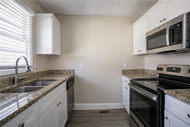 kitchen featuring sink, light stone counters, stainless steel appliances, and white cabinetry