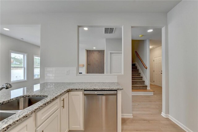 kitchen featuring light hardwood / wood-style floors, dishwasher, light stone countertops, and white cabinetry