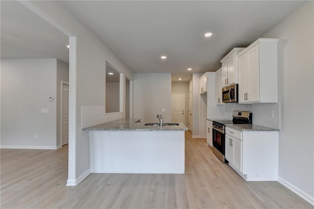 kitchen featuring light hardwood / wood-style flooring, white cabinets, light stone countertops, and stainless steel appliances