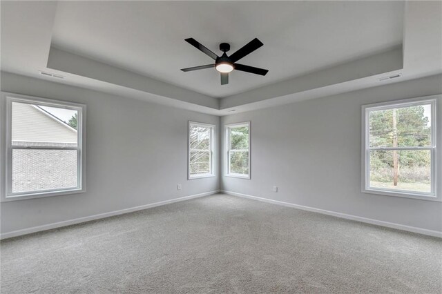 carpeted spare room with a tray ceiling and ceiling fan