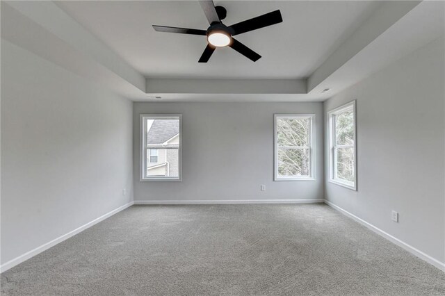 carpeted spare room featuring ceiling fan and a tray ceiling