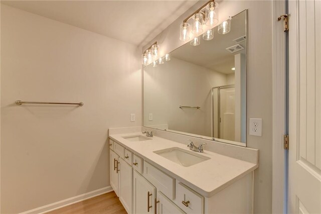 bathroom with vanity, a shower with shower door, and wood-type flooring