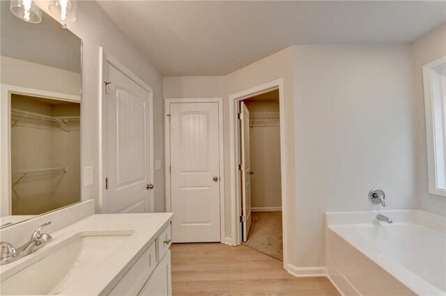 bathroom featuring vanity, a tub to relax in, and hardwood / wood-style flooring