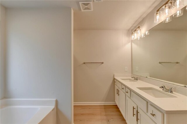 bathroom with vanity, hardwood / wood-style floors, and a tub