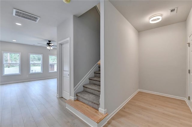 staircase featuring wood-type flooring and ceiling fan