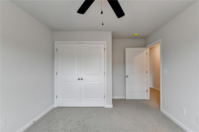 unfurnished bedroom featuring light colored carpet, a closet, and ceiling fan