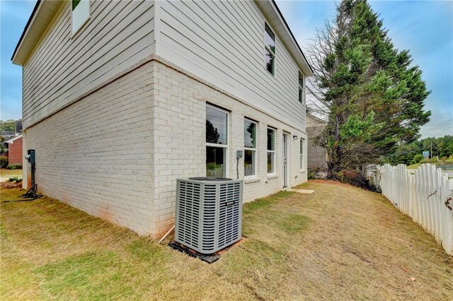 view of side of property featuring central AC and a lawn