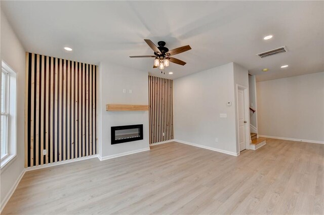 unfurnished living room with a wealth of natural light, light wood-type flooring, and ceiling fan