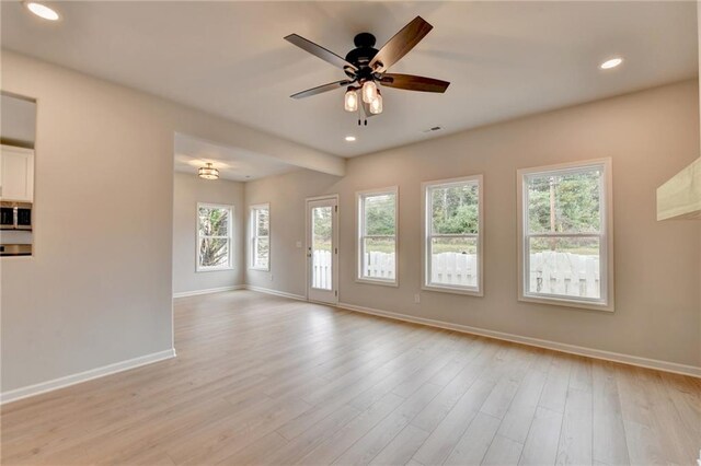 spare room featuring ceiling fan, light hardwood / wood-style floors, and plenty of natural light