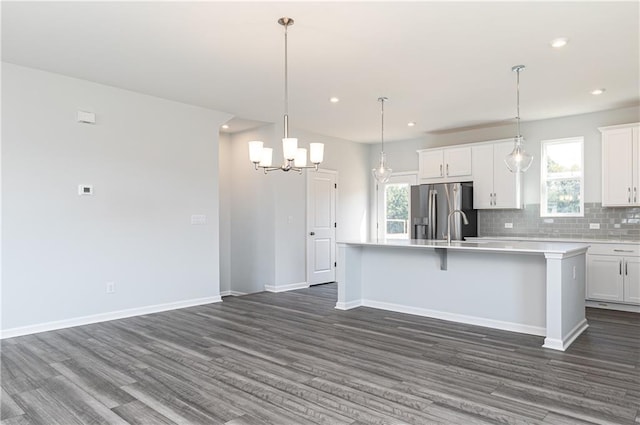 kitchen featuring stainless steel fridge, a center island with sink, and white cabinetry