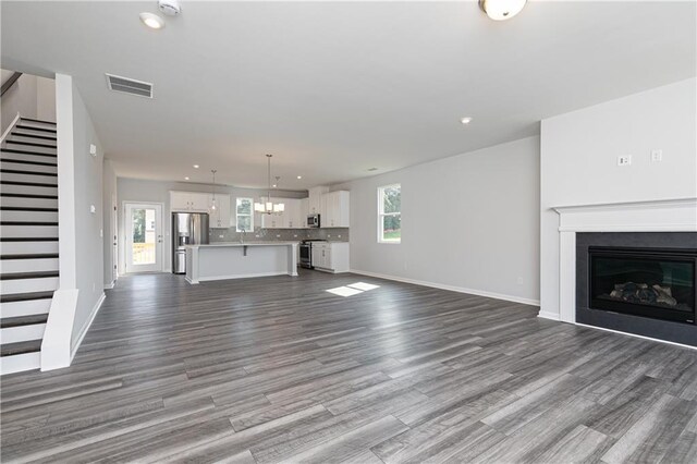 unfurnished living room with wood-type flooring and an inviting chandelier