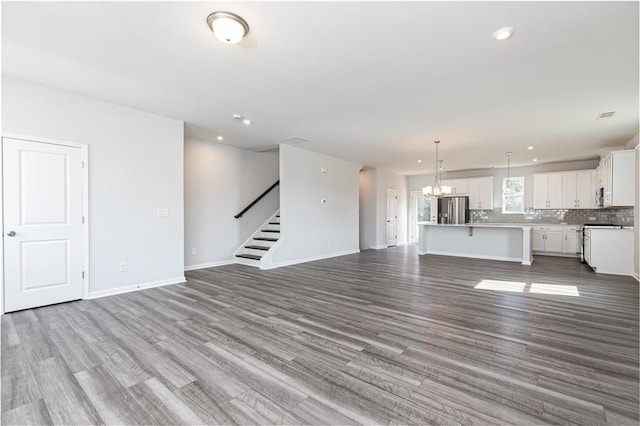 unfurnished living room with light wood-type flooring and an inviting chandelier