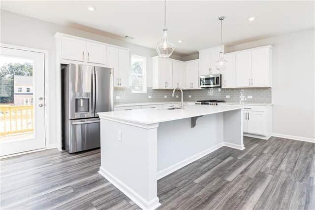 kitchen featuring sink, white cabinetry, stainless steel appliances, and an island with sink