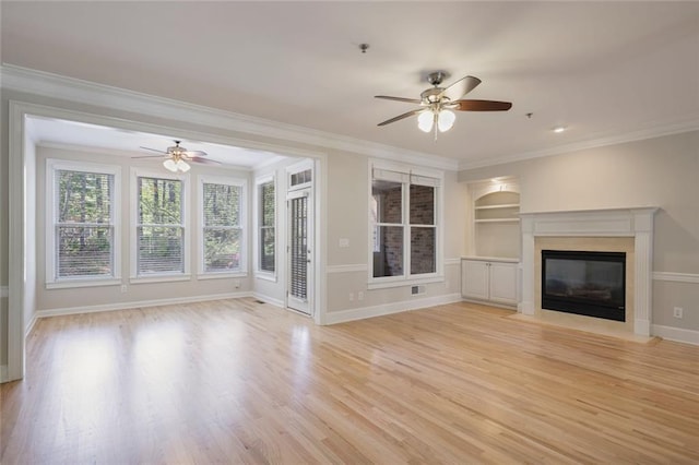 unfurnished living room with crown molding, ceiling fan, a glass covered fireplace, and light wood-style floors