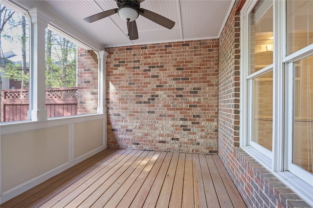 unfurnished sunroom featuring wood-type flooring and brick wall