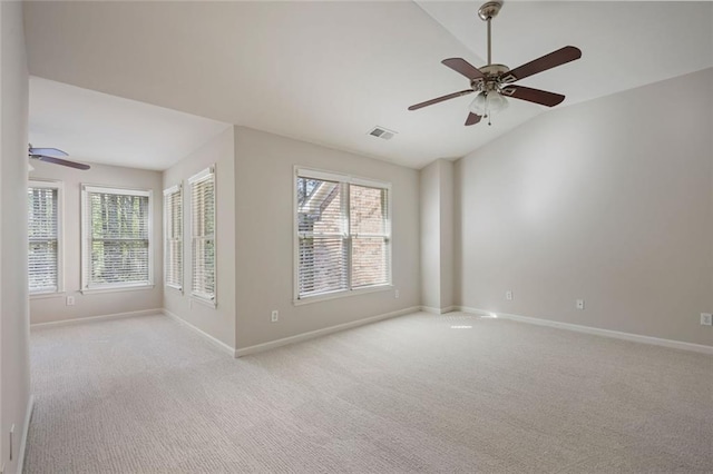 spare room with baseboards, ceiling fan, vaulted ceiling, and visible vents