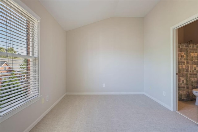 carpeted empty room with baseboards and vaulted ceiling