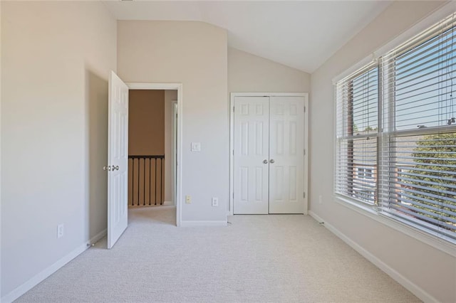 unfurnished bedroom with carpet floors, baseboards, a closet, and lofted ceiling