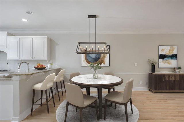 dining area featuring crown molding, recessed lighting, light wood-style flooring, and a chandelier