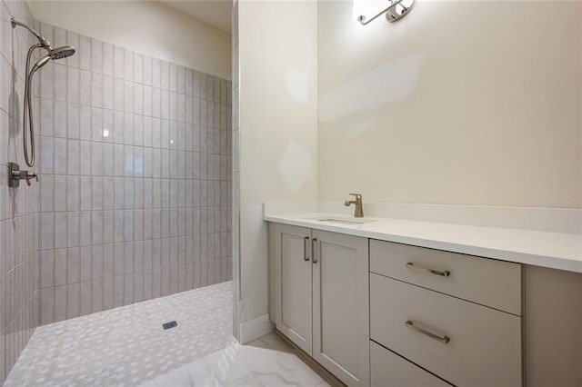 bathroom with a tile shower and vanity