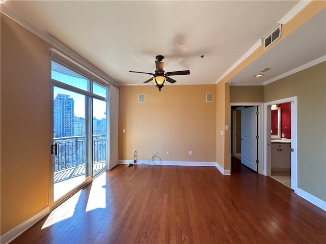 spare room with a view of city, visible vents, ornamental molding, wood finished floors, and baseboards