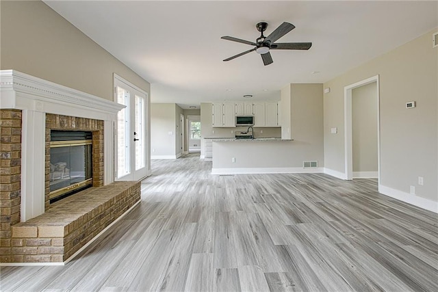 19 Quimby Jackson Rd, Newnan, GA 30263 - unfurnished living room featuring light wood-style flooring, ceiling fan, and a brick fireplace
