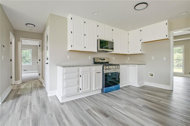 19 Quimby Jackson Rd, Newnan, GA 30263 - kitchen featuring appliances with stainless steel finishes, light wood finished floors, white cabinetry, light countertops, and plenty of natural light