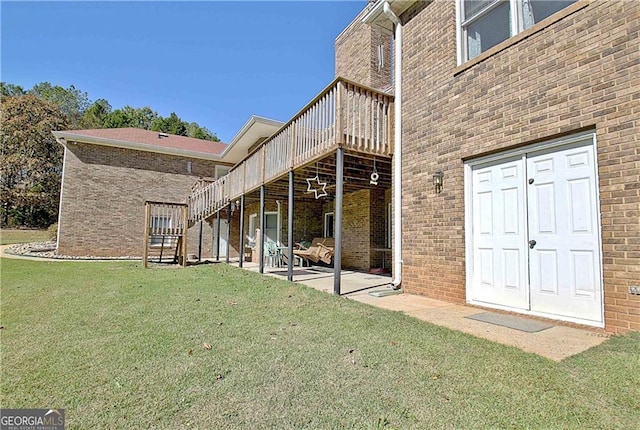 19 Quimby Jackson Rd, Newnan, GA 30263 - back of property with stairway, a wooden deck, a yard, brick siding, and a patio area