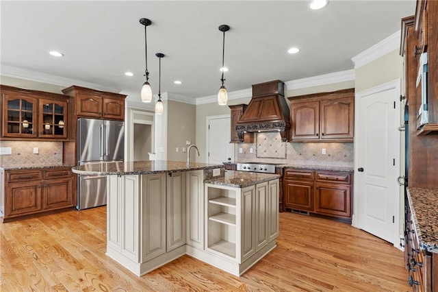 2602 Alcovy Club Dr, Dacula, GA 30019 - kitchen featuring freestanding refrigerator, premium range hood, tasteful backsplash, a kitchen island with sink, and light wood finished floors