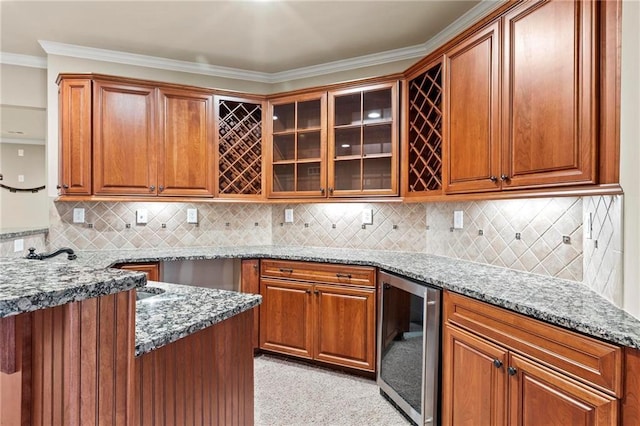 2602 Alcovy Club Dr, Dacula, GA 30019 - kitchen featuring wine cooler, light stone counters, glass insert cabinets, brown cabinetry, and ornamental molding