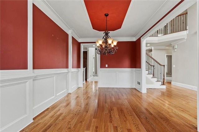2602 Alcovy Club Dr, Dacula, GA 30019 - unfurnished dining area with a chandelier, stairway, light wood-style flooring, a wainscoted wall, and ornamental molding