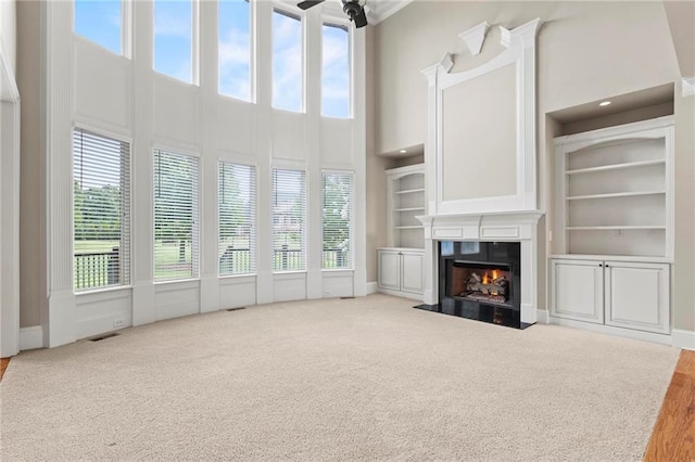 2602 Alcovy Club Dr, Dacula, GA 30019 - unfurnished living room with a towering ceiling, carpet flooring, healthy amount of natural light, a fireplace with flush hearth, and built in shelves