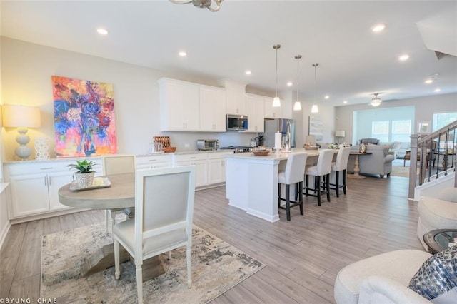 2247 Pink Hawthorn Dr, Buford, GA 30518 - kitchen with appliances with stainless steel finishes, open floor plan, white cabinetry, a center island with sink, and a breakfast bar