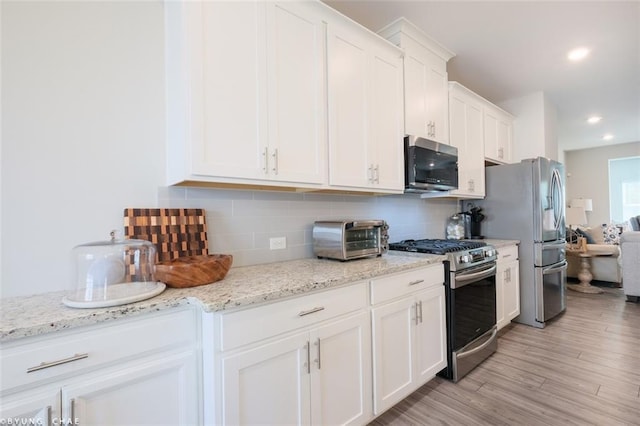 2247 Pink Hawthorn Dr, Buford, GA 30518 - kitchen with stainless steel appliances, white cabinets, tasteful backsplash, light wood-style flooring, and light stone counters