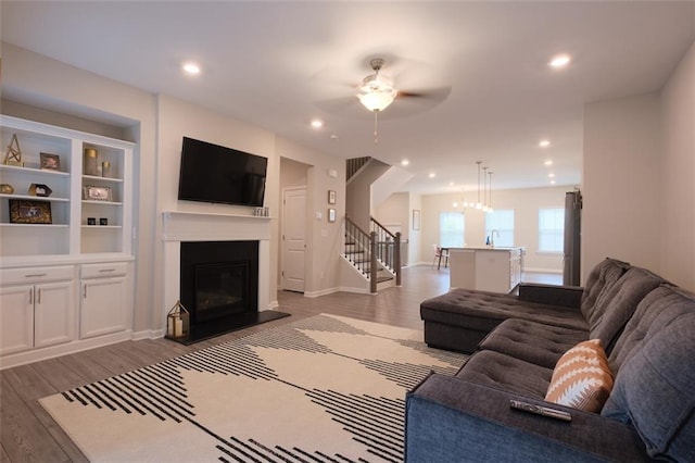2247 Pink Hawthorn Dr, Buford, GA 30518 - living area featuring a glass covered fireplace, wood finished floors, a ceiling fan, stairway, and recessed lighting