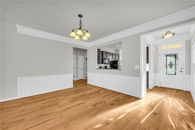 unfurnished dining area featuring ornamental molding, a notable chandelier, and light wood-type flooring