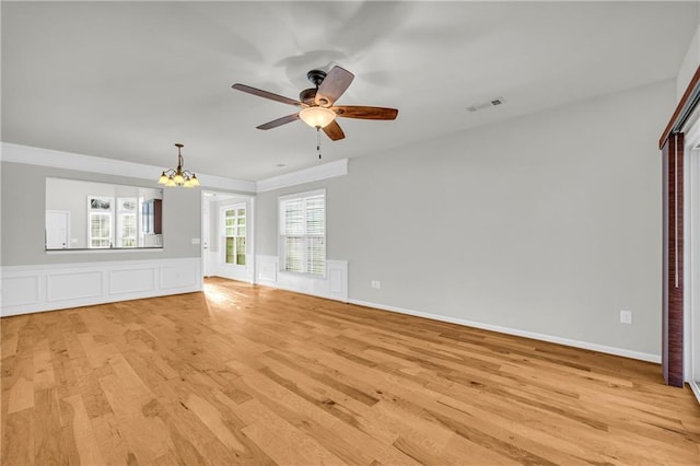 unfurnished living room with ceiling fan with notable chandelier and light hardwood / wood-style floors