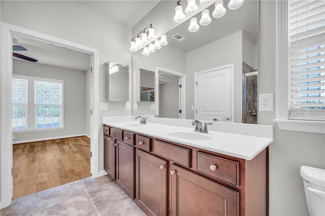 bathroom featuring vanity, toilet, ceiling fan, and walk in shower