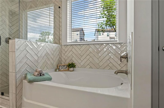 bathroom with a bath and a tile shower