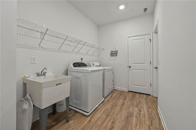 laundry room with separate washer and dryer, light wood finished floors, and baseboards